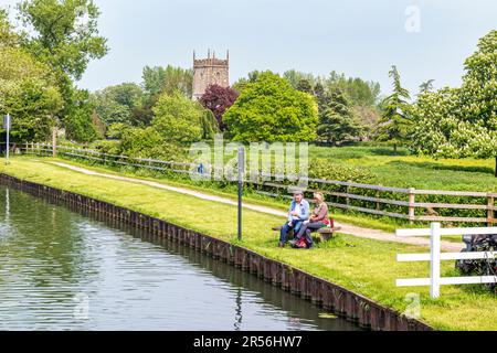 Ein paar Picknicks neben dem Gloucester und Sharpness Canal und der St. Marys Kirche im Severnside Dorf Frampton auf Severn, Gloucestershire UK Stockfoto