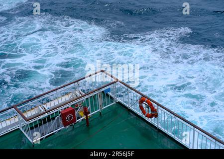 Ein orangefarbenes Rettungsboot auf dem Geländer einer Passagierfähre auf See. Großer Blickwinkel. Stockfoto