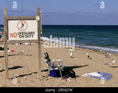 Schild mit der Aufschrift „No Lifeguard on Duty“ und leerer Dolar am Strand von Fort Lauderdale Florida USA Stockfoto