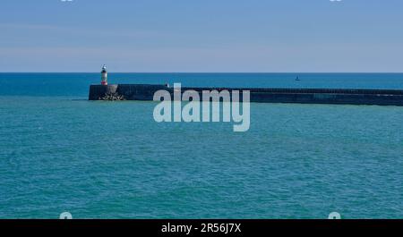 Der Eingang zum Hafen Newhaven, East Sussex, Großbritannien, und seinem Wellenbrecher und Leuchtturm. Blauer Himmel und Wasser im Hintergrund. Stockfoto