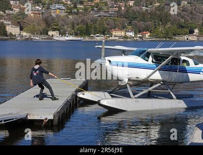 Ein Mann auf einem Ponton, der ein Wasserflugzeug von Cessna Skyhawk II zieht, Como, Italien Stockfoto