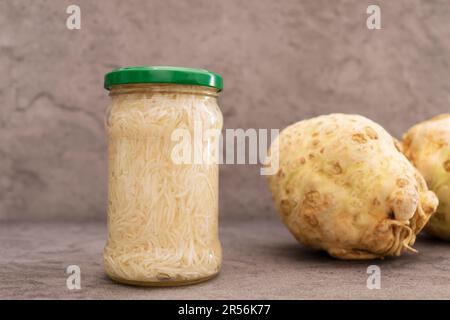 Konservierter, Eingelegter Selleriesalat In Glasdose Mit Metallschraubkappe Auf Dem Regal. Sellerie, Tuber Daneben. Apium Graveolens, Ernte Stockfoto