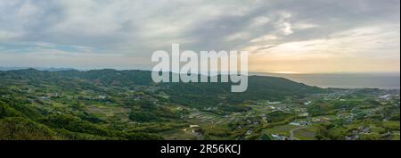 Panoramablick aus der Vogelperspektive auf Bauernhöfe und Felder in grüner Küstenlandschaft Stockfoto
