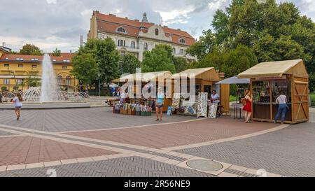 Szeged, Ungarn - 30. Juli 2022: Wasserbrunnen und Souvenir-Kioske am Dugonics-Platz am Sommertag. Stockfoto