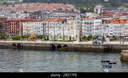 Blick auf die farbenfrohen Gebäude mit lebendigen Fassaden entlang der Uferpromenade mit Blick auf das glitzernde Wasser des Kantabrischen Meeres. Castro-Urdiales, Stockfoto