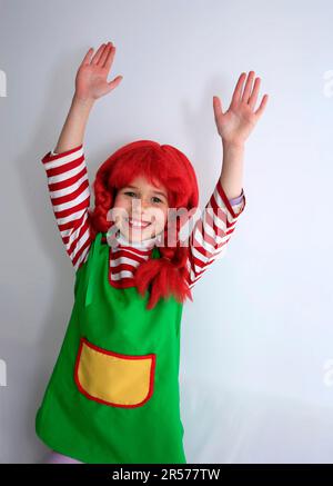 Glückliches Kind, verkleidet als Pippi Langstrumpf für den Karneval, mit roter Perücke und starker Pose Stockfoto