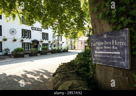 Ein Schild zeigt auf das New Inn and Hotel, das an einen Baum im Yorkshire Dales Dorf Clapham angeschlossen ist. Stockfoto