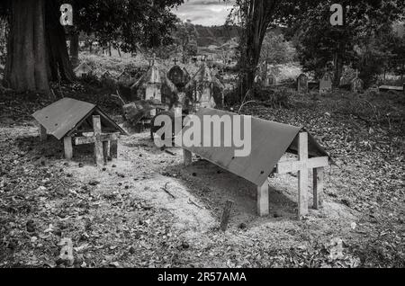 Katholischer Friedhof gegenüber der katholischen Kirche Kon XOM Luh, Kon Ray, Kontum, Vietnam. Ärmere Gräber sind einfach mit rostenden Ölfässern bedeckt. Stockfoto