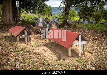 Katholischer Friedhof gegenüber der katholischen Kirche Kon XOM Luh, Kon Ray, Kontum, Vietnam. Ärmere Gräber sind einfach mit rostenden Ölfässern bedeckt. Stockfoto