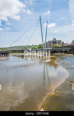 Die Flussufer der Lune bei Ebbe in der Stadt Lancaster, die die Schlammbrücke freilegt, und die Lune Millennium Bridge ist eine Fußgängerbrücke mit Kabelhaltern. Stockfoto