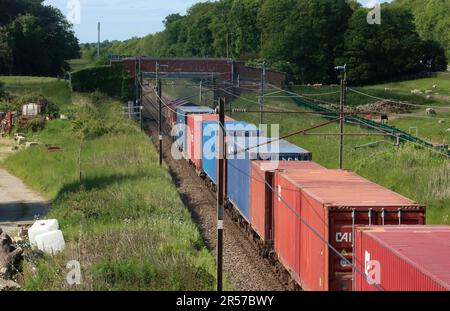 Klasse 66 dieselelektrische Schuppen-Lokomotive im Containerzug auf der Hauptstrecke der Westküste auf dem Land in Woodacre bei Garstang, 1. Juni 2023. Stockfoto