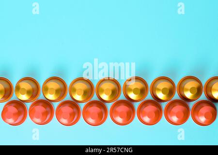 Goldene und rote Kaffeepads hintereinander vor einem schlichten Hintergrund. Ansicht von oben nach unten. Stockfoto