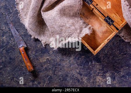 Vintage Metzgermesser und alte Holzkiste auf Steinküchenoberfläche. Draufsicht mit selektivem Fokus Stockfoto