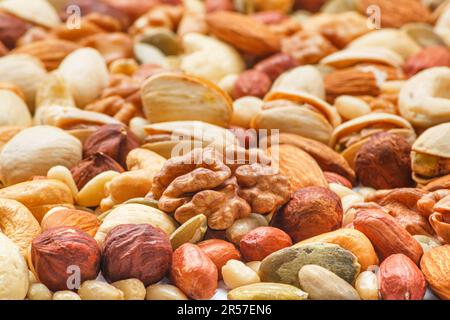 Verschiedene Arten von Nüssen und Samen, Foto mit selektivem Fokus. Geschälte Walnuss, Haselnüsse, geschälte Erdnuss, Pinienkerne, Mandelkerne, Cashewkerne, Stockfoto