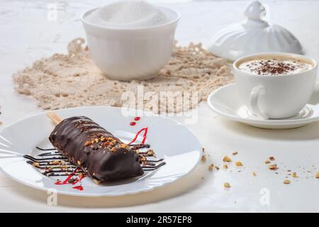 Dessertkuchen auf weißem Teller, Nahaufnahme, selektiver Fokus. Kuchen mit Schokolade und Nüssen bedeckt. Stillleben im Stil eines hohen Schlüssels Stockfoto