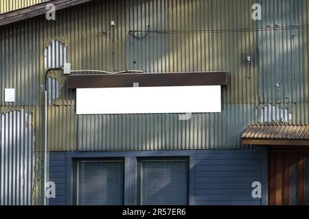 Leeres weißes Schild an einer Metallwand eines alten Industriegebäudes. Stockfoto
