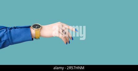 Weibliche Hand mit goldener Armbanduhr auf blauem Hintergrund mit Platz für Text Stockfoto