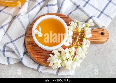 Schüssel mit Honig und Akazienblüten auf hellem Hintergrund, Nahaufnahme Stockfoto
