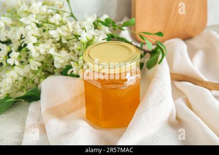 Ein Glas Honig mit Blumen aus Akazien auf dem Tisch, Nahaufnahme Stockfoto
