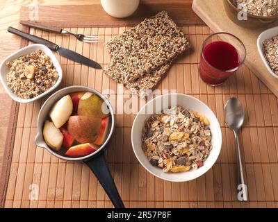 Reichhaltiges Frühstück mit Bio-Cerealien und Zutaten auf einem Holztisch, gesundes Lebensmittelkonzept Stockfoto