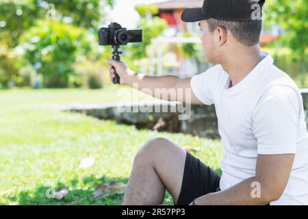 Rückansicht eines jungen lateinamerikanischen Bloggers, der authentische Selbstporträts mit einer Handkamera aufnimmt und seinen Inhalten eine persönliche Note verleiht c Stockfoto