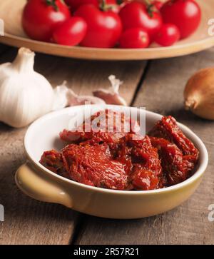 Leckere getrocknete Bio-Tomaten in einer Keramikschale auf einem rustikalen Holztisch, gesunde Lebensmittel oder Zutaten Stockfoto
