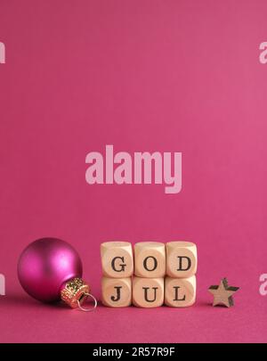 Kleine Holzblöcke mit der Aufschrift God Jul, Scandinavian Merry Christmas, lila Hintergrund, minimalistische Holzweihnachtsdekoration Stockfoto