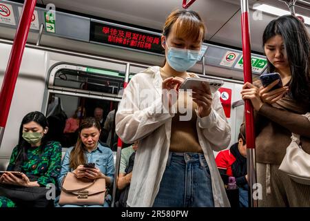 Menschen, die ihre Smartphones in Einem MTR-Zug, Hongkong, China, verwenden. Stockfoto