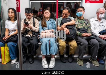 Menschen, die ihre Smartphones in Einem MTR-Zug, Hongkong, China, verwenden. Stockfoto