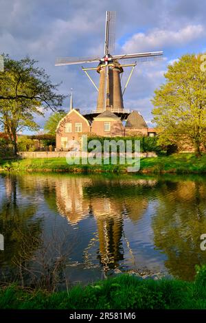 Culemborg, Niederlande - April 25 2023. Windmühle „de Hoop“ in der niederländischen Provinz Gelderland am sonnigen Frühlingstag. Reflexionen im Wasser. Stockfoto