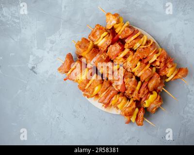 Ungekochte marinierte und geriebene Chiken- oder truthahn-Shish-Kebabs auf Spießen zum Grillen oder Grillen. Rohes Fleisch in einer Marinade mit Gewürzen auf einem freundlichen Stockfoto