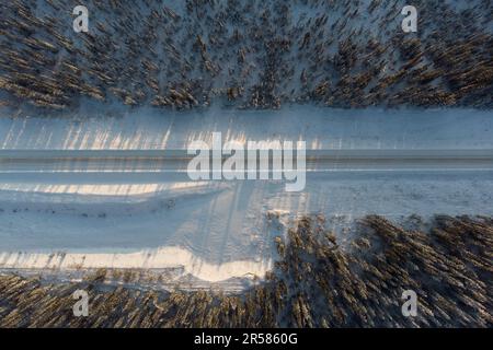 Winterdrohne, unvergleichliche Aussicht auf den nördlichen Klondike Highway in Richtung Dawson City mit Schnee über der wunderschönen arktischen Landschaft. Schneestraße Stockfoto