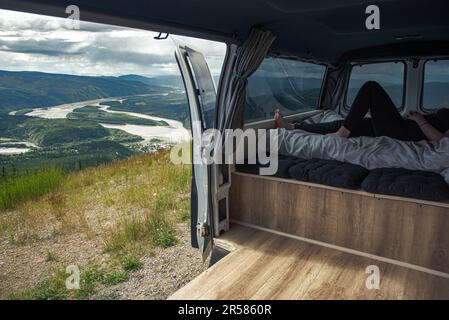 Blick vom Gipfel von Dawson City im Sommer von einem Wohnmobil aus, eine Person mit weitläufiger Wildnis am Yukon River. Stockfoto