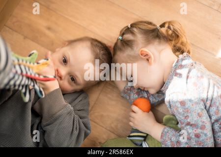 Boy mit Down-Syndrom und ASD spielt mit seiner jüngeren Schwester im Schlafzimmer Stockfoto