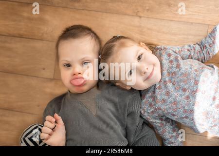 Boy mit Down-Syndrom und ASD spielt mit seiner jüngeren Schwester im Schlafzimmer Stockfoto