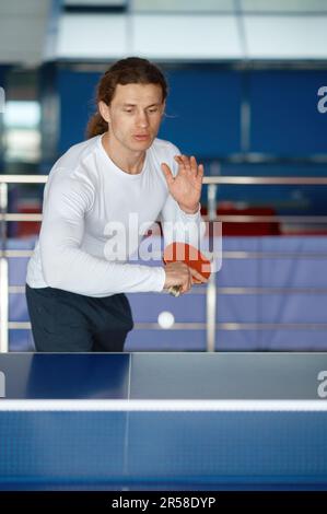 Porträt eines glücklichen männlichen Sportlers, der Tischtennis im Trainingssportclub spielt Stockfoto