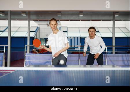 Mann und Frau im Team spielen zusammen Tischtennis im Haus Stockfoto