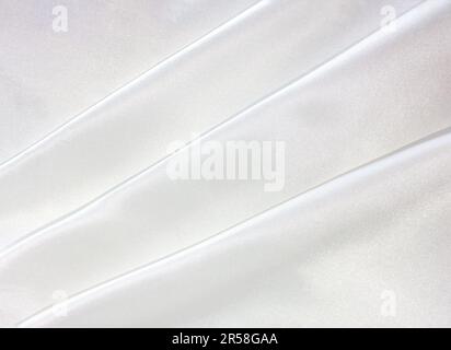 Eine Naht aus weißem Seidenstoff mit Wellenstruktur. Weißer Satin. Gerade, elegante Kurven aus luxuriösem, glänzendem Seidenstoff. Stockfoto