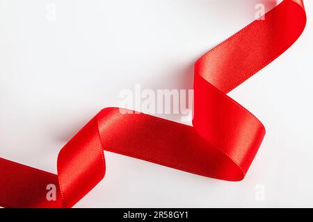 Rotes Seidenband zum Einwickeln von Geschenken auf weißem Hintergrund. Locken aus dekorativem Weihnachtsband. Element für Konstruktion. Stockfoto