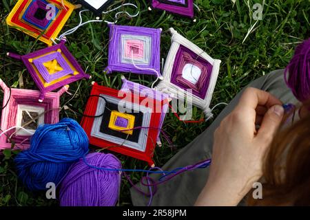 Ein Mädchen macht indische Amulette-Mandalas „Ojos de dios“ (Gottes Augen) in einem Park Stockfoto