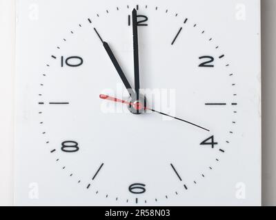 Eine Wanduhr isoliert auf weißem Hintergrund. Es ist 11 Uhr. Stockfoto