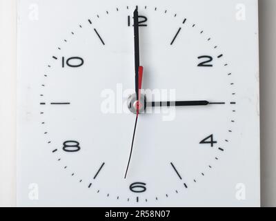 Eine Wanduhr isoliert auf weißem Hintergrund. Es ist 3 Uhr. Nahaufnahme, Konzept, niemand. Stockfoto