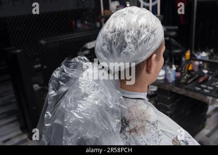 Der Kopf eines Kunden in einem Friseur in Plastikfolie, der Prozess des professionellen Haarfärbens in einem Friseursalon. Stockfoto