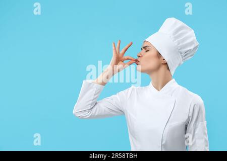 Die Köchin zeigt das perfekte Schild auf hellblauem Hintergrund. Platz für Text Stockfoto