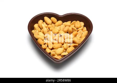 Weiße herzförmige Schale mit getrockneten Früchten (Erdnüsse, Walnüsse, Haselnüsse), isoliert auf weißem Hintergrund. Stockfoto