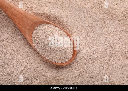 Löffel auf Stapel aktiver Trockenhefe, Draufsicht. Platz für Text Stockfoto