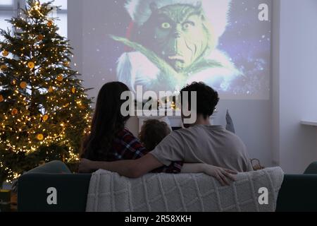 Lemberg, Ukraine – 24. Januar 2023: Die Familie schaut sich den Weihnachtsfilm „How the Grinch Steal“ zu Hause über einen Videoprojektor an, Rückansicht Stockfoto