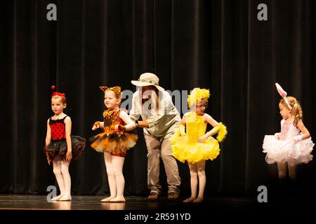 Kleine Mädchen führen mit Hilfe eines Lehrers eine Tanzroutine durch. Stockfoto