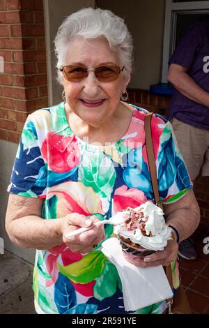 Eine ältere Frau in einem farbenfrohen Hemd lächelt, als sie gerade einen Eisbecher bei Händels hausgemachter Eiscreme in Fishers, Indiana, USA, isst. Stockfoto