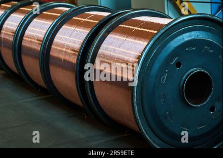 Riesige Rollen mit glänzendem Kupferdraht im Fabriklager Stockfoto